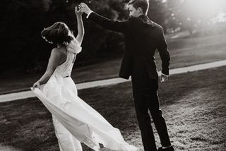 Mustavalkoinen kuva hääparista tanssimassa nurmikolla.