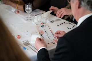 Häävieras tutkii hääjuhlan ohjelmaa ruokapöydässä