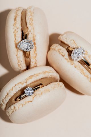 Kolme timanttisormusta beigenväristen macarons-leivosten sisällä